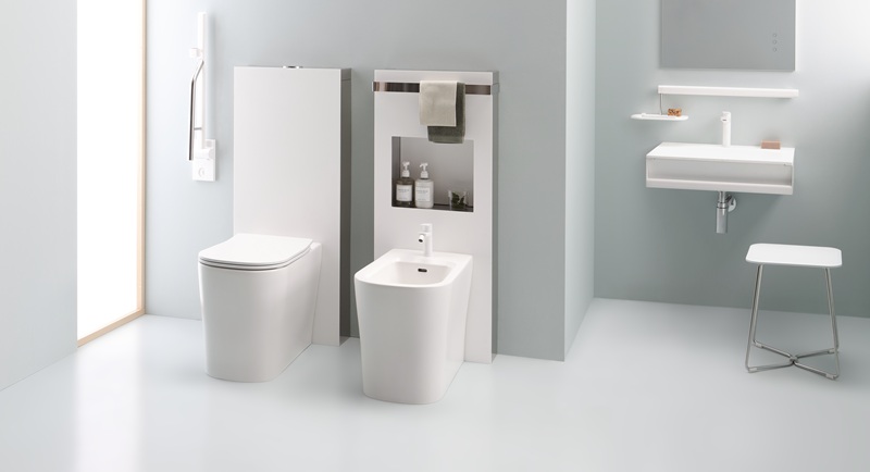Vaso e bidet bianchi da terra, pannelli con nicchia, maniglione, lavabo sospeso, sgabello in acciaio